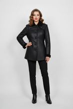 Įkelti nuotrauką į galerijos peržiūros programą, A woman modeling a black faux-leather peplum coat with a high collar and black buttons, paired with black pants and black ankle boots, against a light gray studio background.