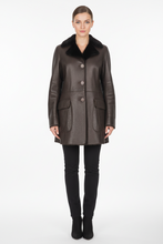 Įkelti nuotrauką į galerijos peržiūros programą, A woman stands facing forward wearing a dark brown leather coat with a black fur-like collar, black pants, and black ankle boots against a plain light gray studio background.