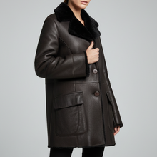 Įkelti nuotrauką į galerijos peržiūros programą, A woman modeling a dark brown leather coat with a black faux-fur collar, paired with black pants, against a solid light gray studio background.