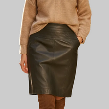 Įkelti nuotrauką į galerijos peržiūros programą, A woman modeling a beige ribbed turtleneck sweater and a black faux-leather pencil skirt against a solid gray background.