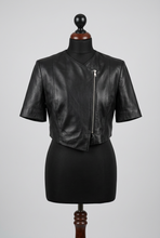 Įkelti nuotrauką į galerijos peržiūros programą, A black short-sleeve cropped faux-leather jacket with a front zipper, displayed on a black dress form mannequin against a light gray background.