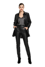 Load image into Gallery viewer, A woman modeling a black faux leather jacket, matching black faux leather pants, a black satin top, and black ankle boots against a plain white studio background.