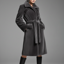 Įkelti nuotrauką į galerijos peržiūros programą, A model wears a dark gray plush faux fur coat with a matching waist belt, paired with black knee-high boots, against a neutral gray studio background.
