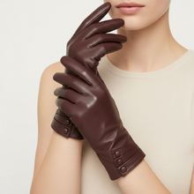 Įkelti nuotrauką į galerijos peržiūros programą, A close-up of a model wearing dark brown leather gloves, with one glove resting on the other. The model is wearing a light beige knit top against a clean, light off-white background.