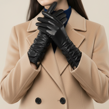 Įkelti nuotrauką į galerijos peržiūros programą, A close-up of a model wearing a beige double-breasted coat and long black leather gloves, with a dark blue top visible at the neckline.