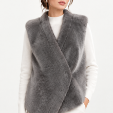 Load image into Gallery viewer, A woman wearing a gray faux fur wrap vest over a white ribbed sweater and white pants, photographed against a clean white studio background.