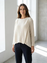 Load image into Gallery viewer, Woman wearing a beige linen sweater and dark pants in a bright room.