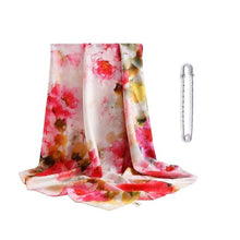 Load image into Gallery viewer, A square silk scarf with a floral pattern in red, pink, and white colors, displayed alongside a white metal brooch.