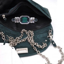 Load image into Gallery viewer, A green suede crossbody bag with a metal brooch featuring rhinestones, a chain strap, and a zipper closure.