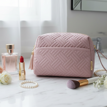 Įkelti nuotrauką į galerijos peržiūros programą, Pink quilted makeup bag on a bathroom counter with cosmetics and flowers.