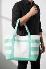 Load image into Gallery viewer, Person holding a striped tote bag with green and white colors against a neutral background