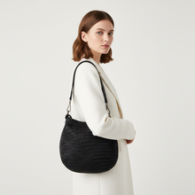 Load image into Gallery viewer, Woman holding a black woven handbag against a white background