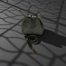 Load image into Gallery viewer, Woven leather bag with strap on a dark surface with shadow patterns