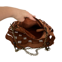 Load image into Gallery viewer, Brown leather handbag with chain detail held by a hand on a white background