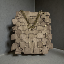 Load image into Gallery viewer, Beige woven handbag with gold chain on a gray background