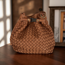 Load image into Gallery viewer, Brown woven handbag on a wooden surface with a blurred background