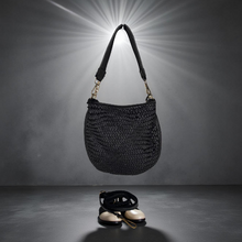 Load image into Gallery viewer, Black woven handbag hanging against a dark background with a spotlight effect.