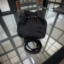 Load image into Gallery viewer, Black woven handbag with a strap on a reflective surface