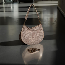 Load image into Gallery viewer, Woven handbag on a reflective black surface with a blurred indoor background