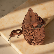Load image into Gallery viewer, Brown leather bag with intricate cut-out design on a beige surface