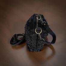 Load image into Gallery viewer, Black textured handbag with a strap on a brown surface