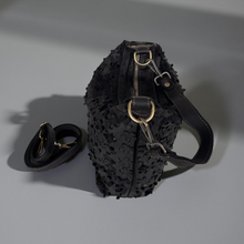 Load image into Gallery viewer, Black textured handbag with gold accents on a gray background