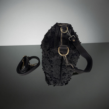 Load image into Gallery viewer, Black textured bag with gold accents on a reflective surface