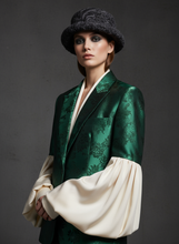 Load image into Gallery viewer, Model wearing a green brocade jacket with a white garment underneath against a dark background
