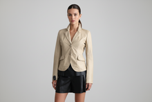 Load image into Gallery viewer, Woman wearing a beige blazer and black skirt on a gray background