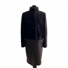 Load image into Gallery viewer, A chocolate brown knee-length sheepskin fur coat with astrakhan (karakul) fur decoration, displayed on a mannequin. It features a stand turtleneck collar, press-stud fastening, and front pockets.