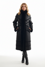 Įkelti nuotrauką į galerijos peržiūros programą, A woman modeling a long black coat with structured paneling and a high collar, paired with black knee-high boots, against a plain white studio background.