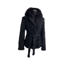 Load image into Gallery viewer, Black astrakhan (karakul) hip-length jacket with black dyed Bluefox collar and fur hooks fastening. Pockets are visible at the front, and there is a tie at the waist.