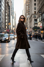 Įkelti nuotrauką į galerijos peržiūros programą, A woman wearing a dark brown textured teddy coat, black pants, and black high-heeled boots walks across a city crosswalk during the day.