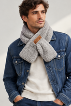 Įkelti nuotrauką į galerijos peržiūros programą, A man wearing a thick, cozy light gray sherpa fleece scarf with a small brown leather brand patch, styled over a cream sweater and a blue denim jacket.