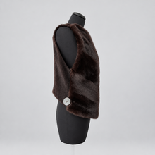 Load image into Gallery viewer, A dark brown faux fur vest displayed on a black mannequin torso, featuring a single white button on the side, set against a light gray background.