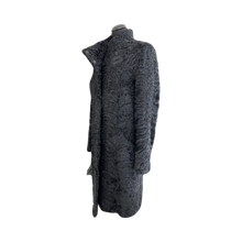 Load image into Gallery viewer, A long black astrakhan fur coat with a stand collar and front pockets, featuring press studs fastening and an inner lining.