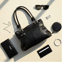 Load image into Gallery viewer, Black handbag with sunglasses, wallet, and other accessories on a beige surface