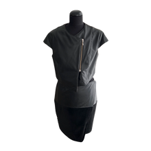 Load image into Gallery viewer, Short sleeves black sheep leather mini jacket on a mannequin, with interlining visible at the front and a zipper at the top. The mannequin is wearing a black dress and the jacket is displayed with a black belt.