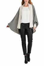 Load image into Gallery viewer, A woman modeling a black and white houndstooth open-front drape cardigan with a solid cream collar, worn over a white top and black faux-leather pants on a white studio background.