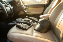 Load image into Gallery viewer, Black gloves and cap on a car seat with a blurred outdoor background