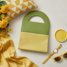 Load image into Gallery viewer, Green and yellow handbag with flowers, a watch, and sunglasses on a light background