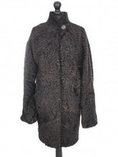Load image into Gallery viewer, A dark brown astrakhan short coat with decorative textile inserts, featuring front pockets and fur hooks fastening, displayed on a mannequin.