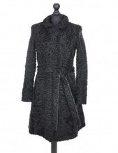 Load image into Gallery viewer, Black astrakhan knee-length coat with a tie, pockets at the front, and fur hooks fastening, displayed on a mannequin.