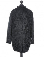 Load image into Gallery viewer, Black astrakhan cacoon type coat with pockets at the front and fur hooks fastening, displayed on a mannequin.
