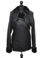 Load image into Gallery viewer, A black, long Nappa merino sheepskin fur jacket with buttons, a collar, and front pockets, displayed on a mannequin.