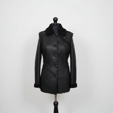 Įkelti nuotrauką į galerijos peržiūros programą, Black long Nappa Merino sheepskin fur fitted jacket with buttons opening, regular collar, and pockets at the front displayed on a mannequin.