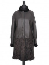 Load image into Gallery viewer, A chocolate brown knee-length sheepskin coat with astrakhan fur decoration, featuring a stand turtleneck collar, press-stud fastening, and front pockets. The coat is displayed on a mannequin.
