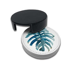Load image into Gallery viewer, A set of round leather coasters with a blue palm leaf pattern, including a black holder with a buckle closure.