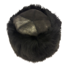 Load image into Gallery viewer, A round black sheepskin hat with shiny leather on top.