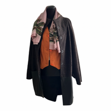 Load image into Gallery viewer, A brown wool cocoon style midi length cardigan with leather trim and press-studs fastening, lined inside, displayed on a mannequin with a pink floral scarf and an orange jacket.